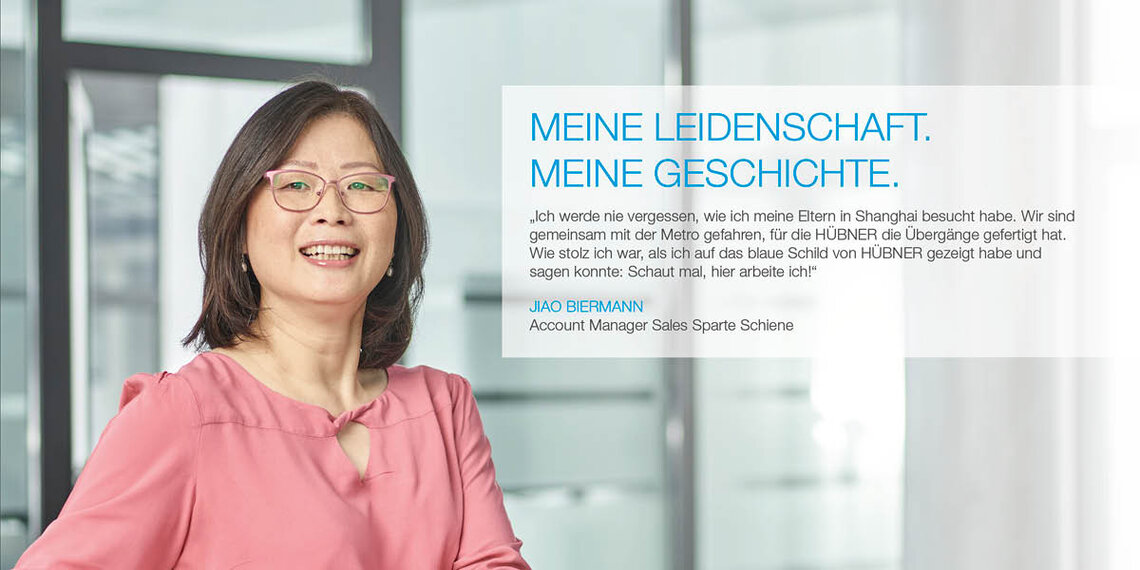 Mitarbeiterin im Büro mit Zitat: "Ich werde nie vergessen, wie ich meine Eltern in Shanghai besucht habe. Wir sind gemeinsam mit der Metro gefahren, für die HÜBNER die Übergänge gefertigt hat. Wie stolz ich war, als ich auf das blaue Schild von HÜBNER gezeigt habe und sagen konnte: Schaut mal, hier arbeite ich!" Jiao Biermann, Account Manager Sales Sparte Schiene