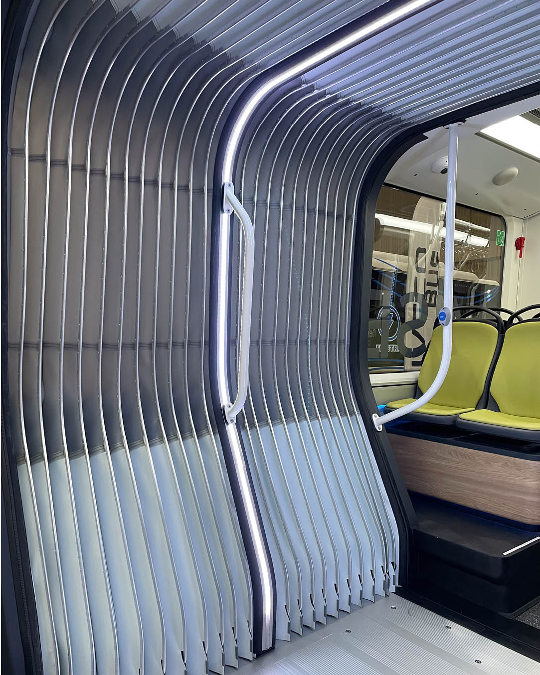 Interior view of a modern bus featuring a accordion system that stands out with its curved shape and LED lighting.